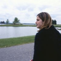 Woman sitting near lake, looking at landscape