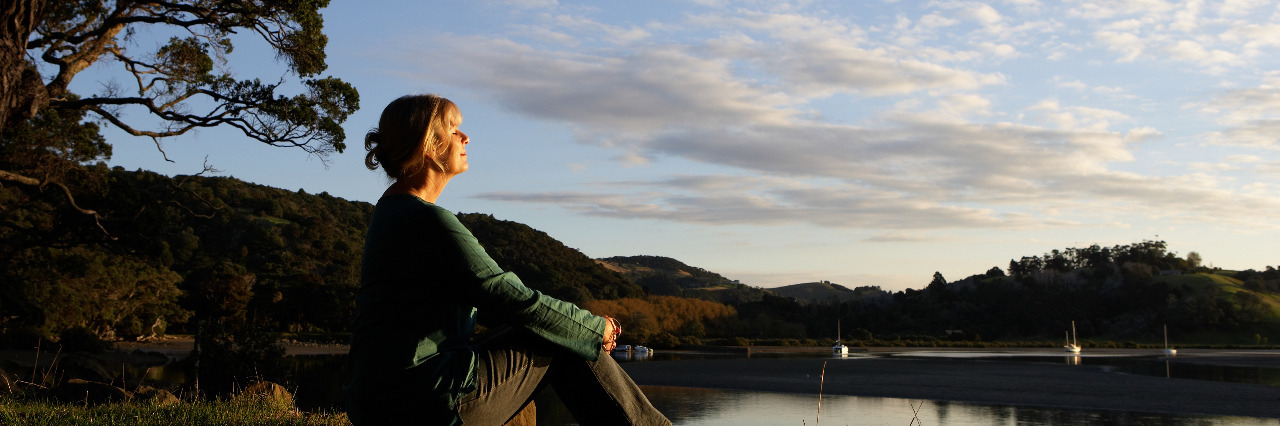 Woman sitting by lake.