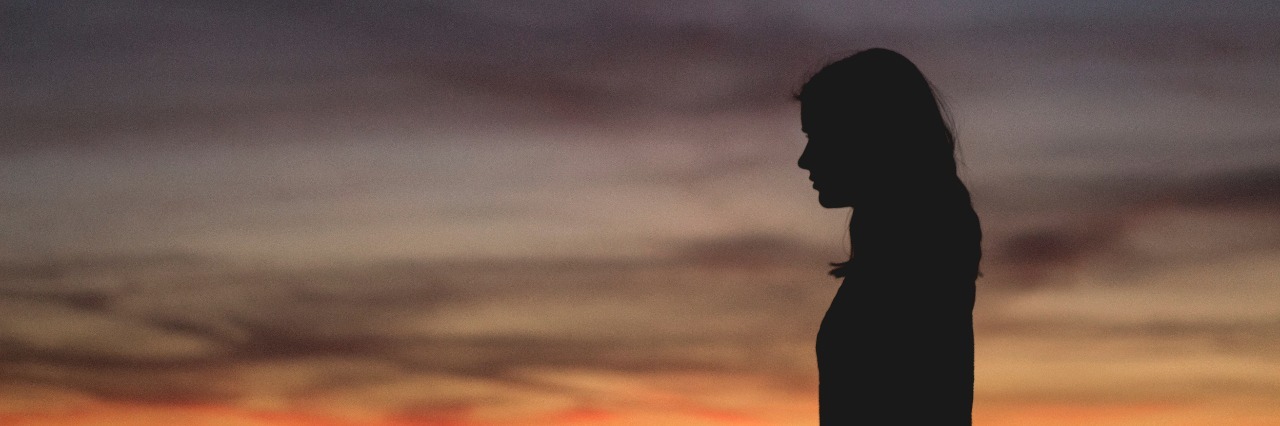 woman silhouetted against sunset sky