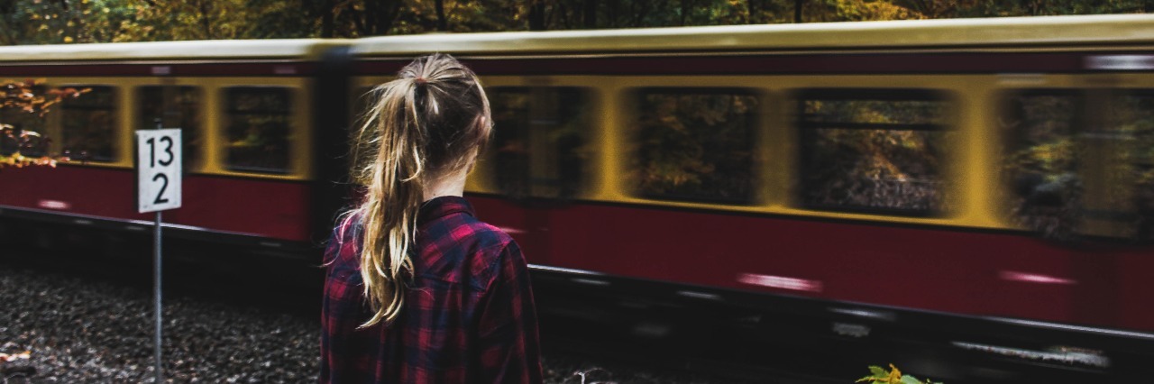 young woman watching train pass by in wooded area