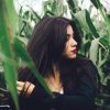 dark haired woman in cornfield lost in thought