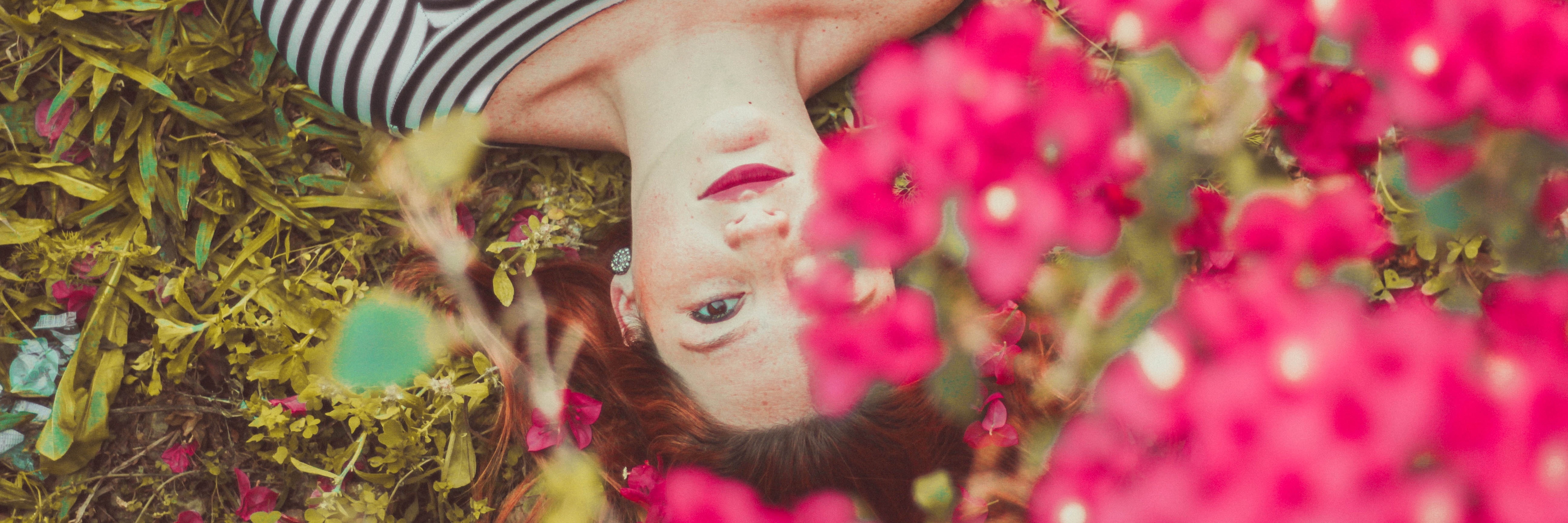 young woman lying among pink flowers in spring garden