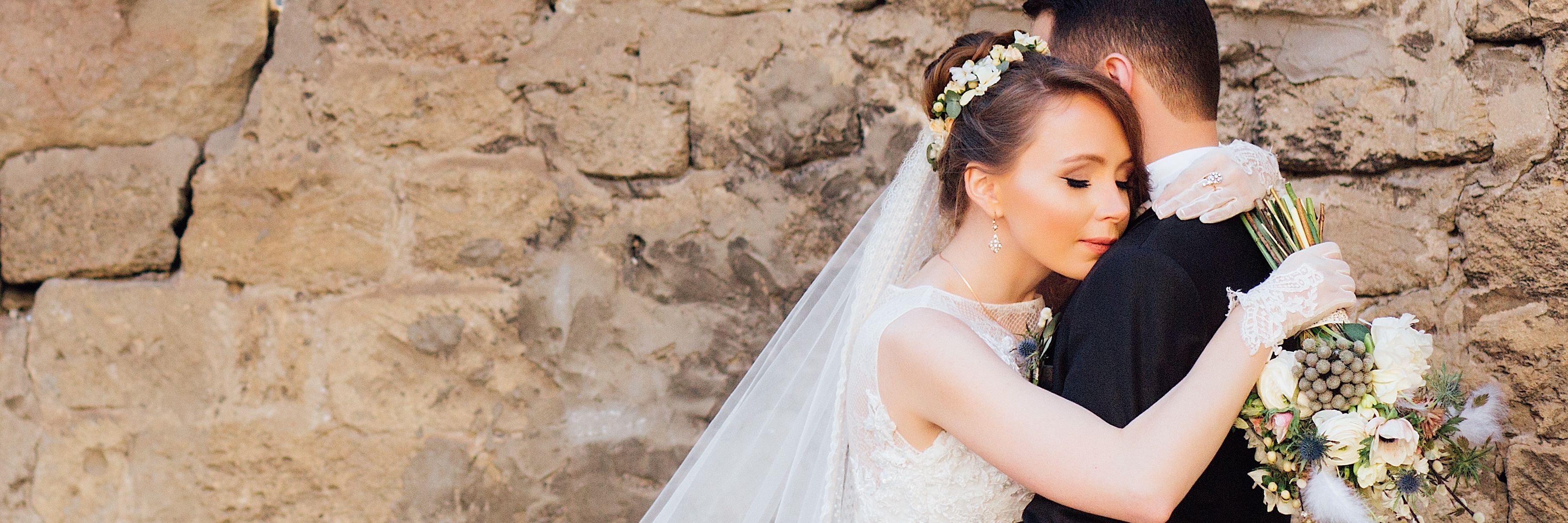 How PTSD Affected My Wedding Night newly wed husband and wife embracing before stone wall