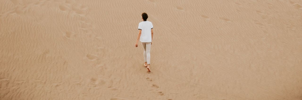 person walking on sand dune