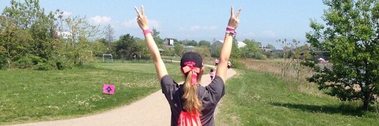 girl walking down a path with her hands raised in peace signs
