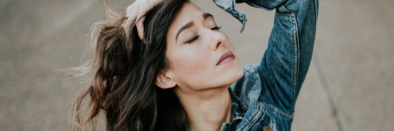 What I Learned When I Traveled and My Depression Followed Me image of woman sitting on pavement with hands running through hair