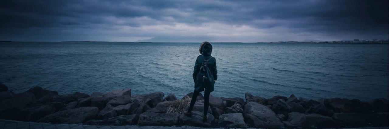 Why My Depression Is Like a Power Outage woman standing in front of stormy sea and stormy sky