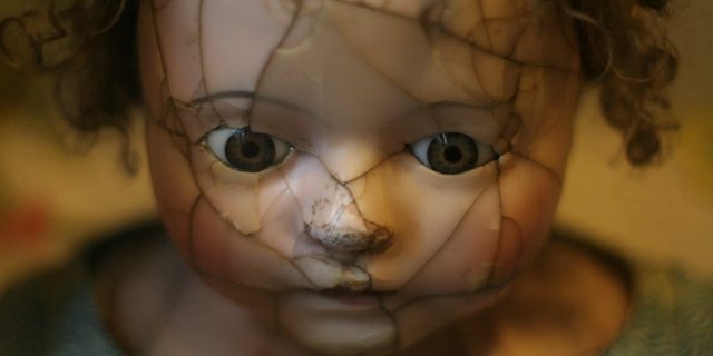 Shattered and Broken: Grief Is Our Name and We Are Beautiful Close up of a doll's face with a shattered face