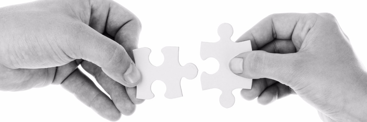 black and white image of hands holding jigsaw pieces