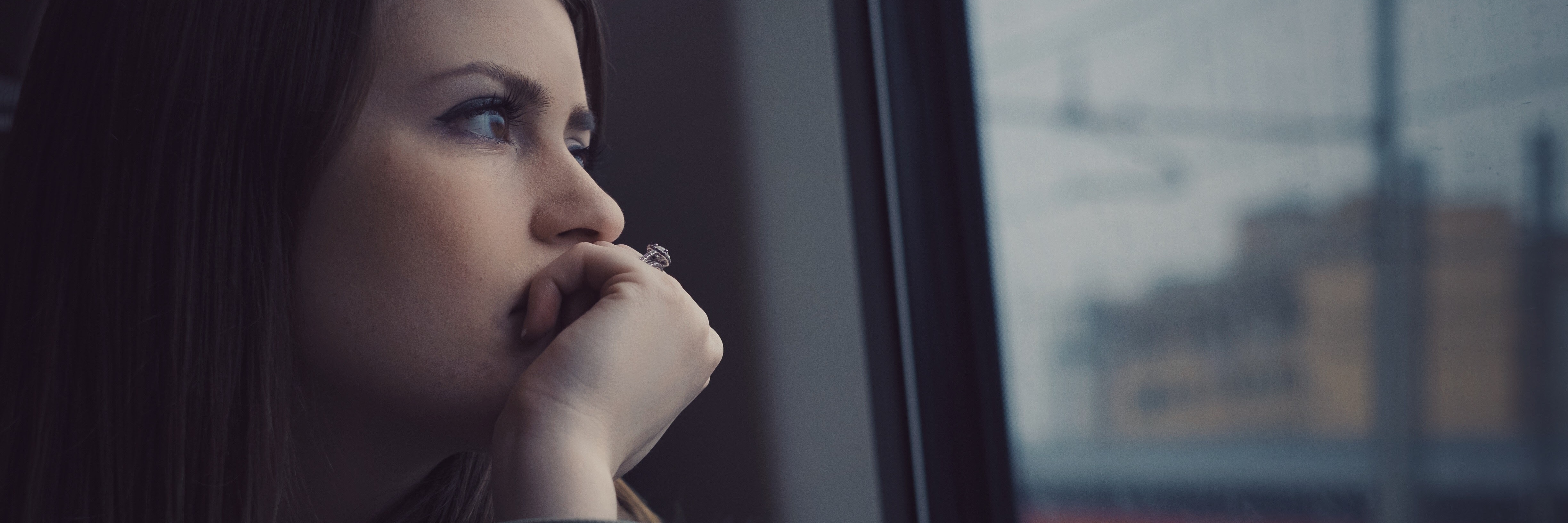 young woman staring out of public transport window looking pensive or anxious