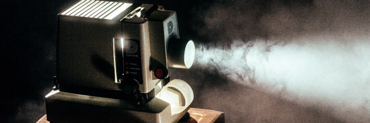 old movie projector sitting on wooden table with light shining through fog