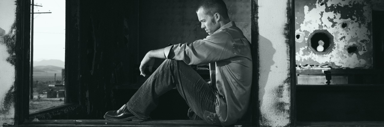 Why Living With Bipolar Disorder Is Exhausting man sitting in derelict building looking depressed