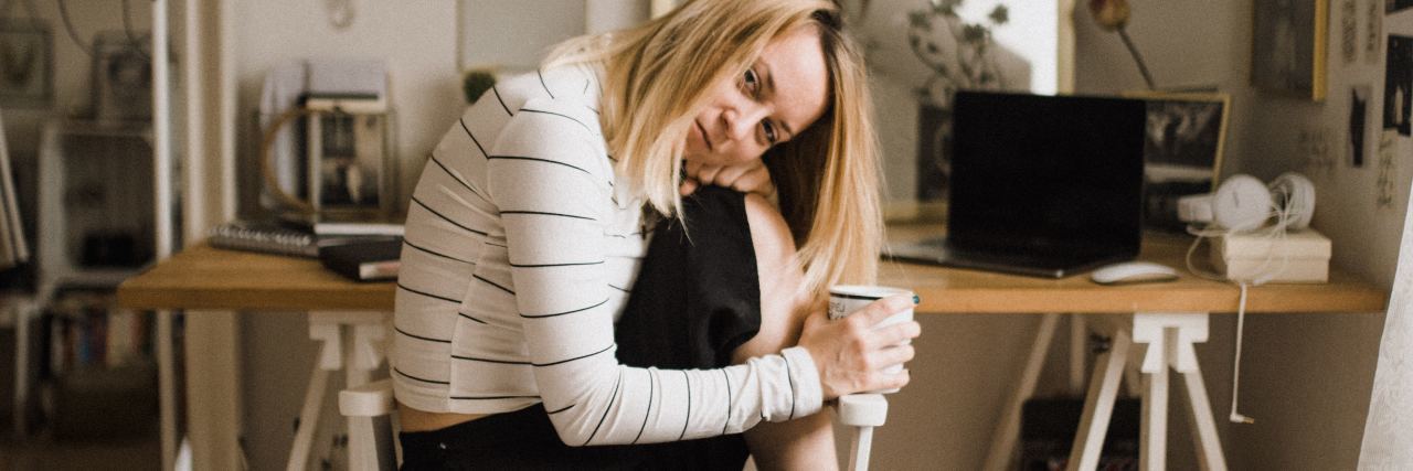 What to Know About Being a Business Owner With a Mental Illness photo of blonde entrepreneur woman sitting in front of workspace smiling for camera