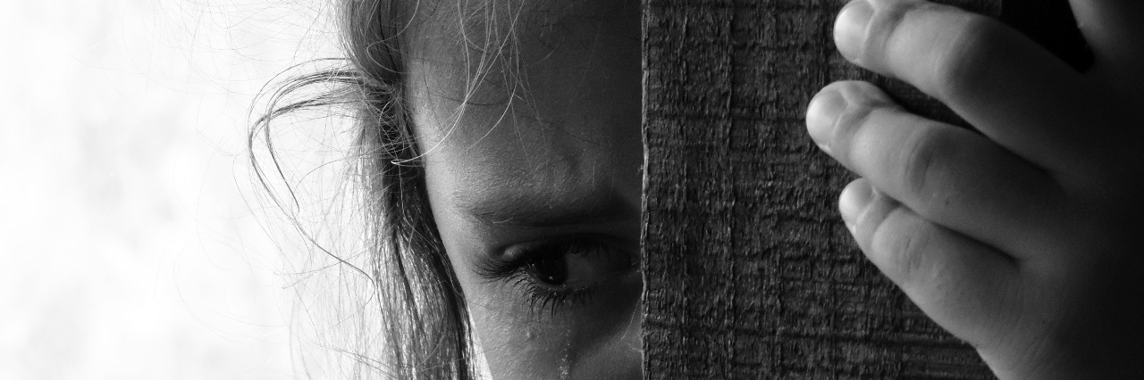 What You Have to Know as a Teen With Anxiety teenage girl behind wooden beam with tears in her eyes