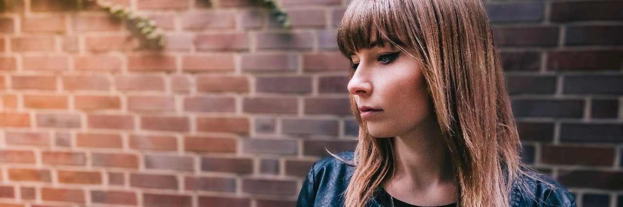 What I Want Others to Know About Suicidal Ideation girl in front of brick wall
