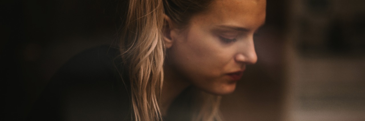 Side profile photo of young blonde woman looking depressed