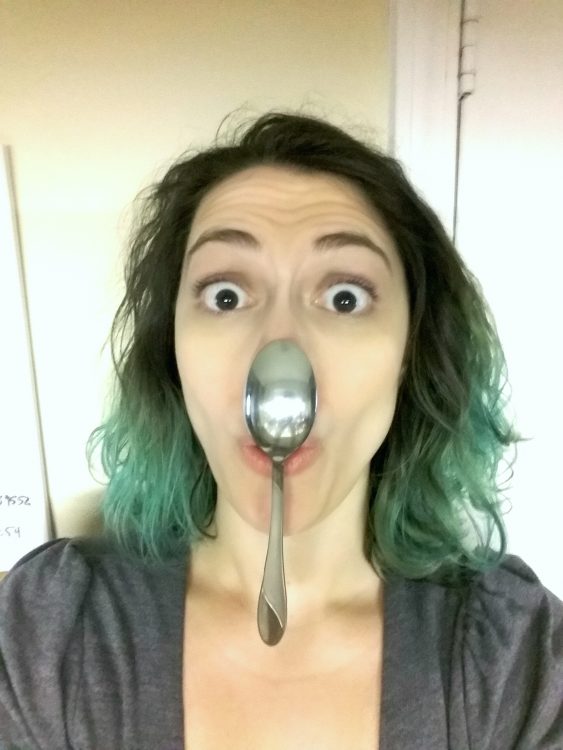 A female with a spoon on her nose.
