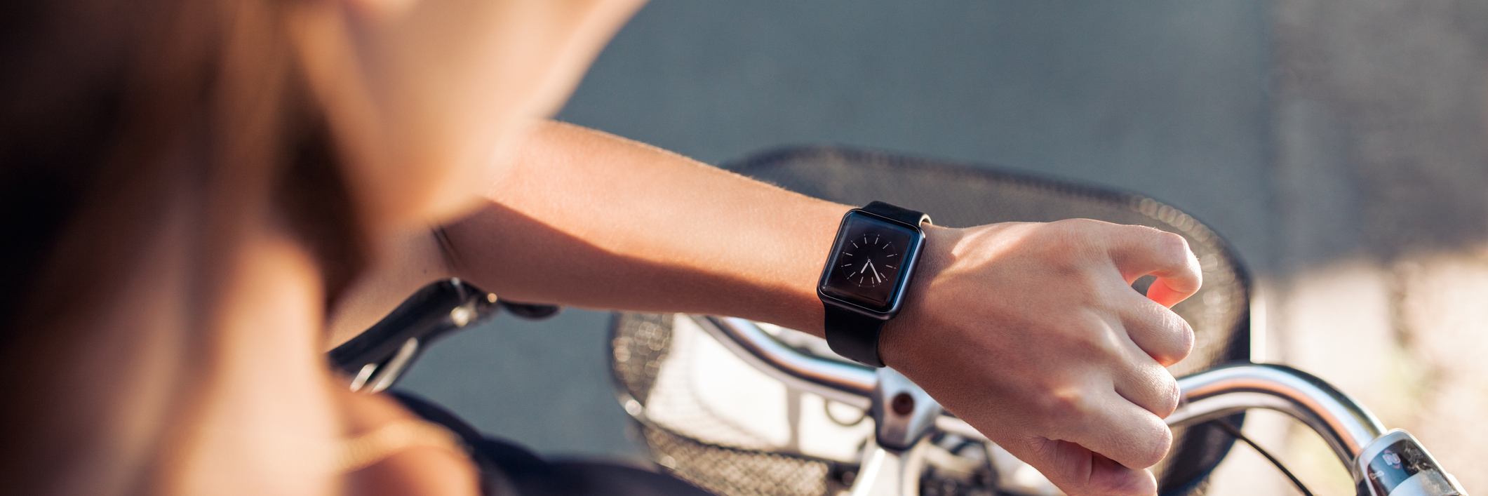 Woman with a bicycle looking at her smartwatch. Close up shot of female checking time on her smart wristwatch.
