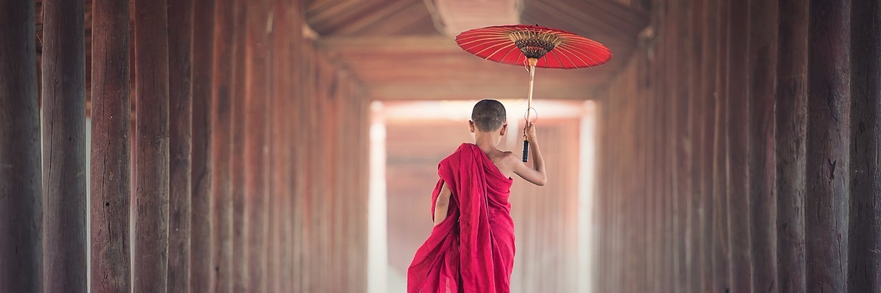 Why I'm Grateful to Fibromyalgia young boy wearing the clothes of a buddhist monk runs down a hallway carrying an umbrella