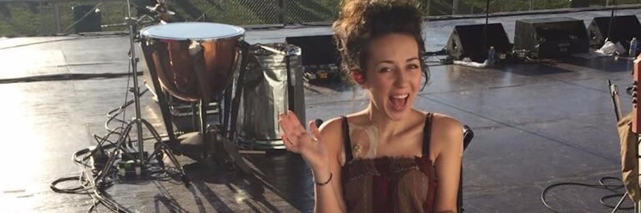 Appreciating the Miracle of Life With Chronic Illness young woman sitting in a wheelchair on a stage looking over crowd of people