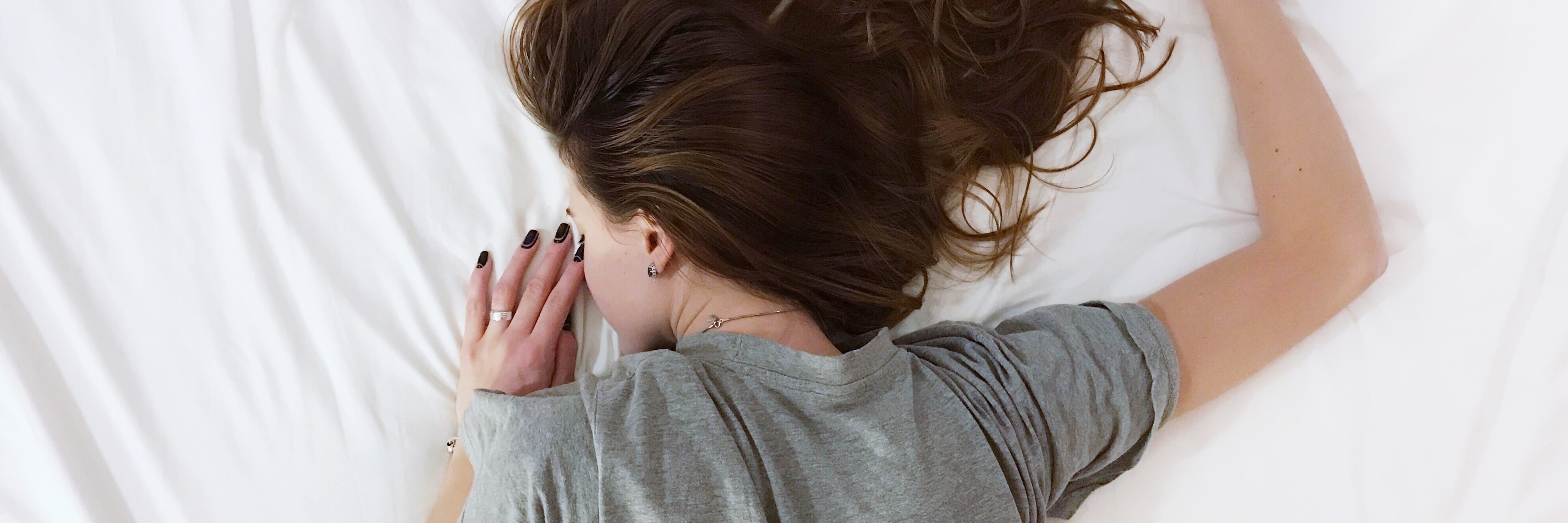 Challenging Bipolar Disorder Stigma and Misconception woman lying face down on white sheets on bed with hair spread