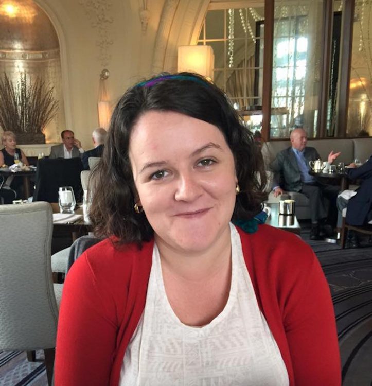 A woman sits in a restaurant smiling.