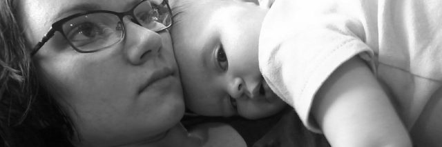 black and white photo of woman lying down with baby sleeping on top of her
