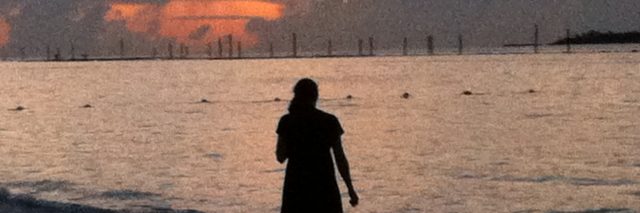 woman standing on the beach at sunset