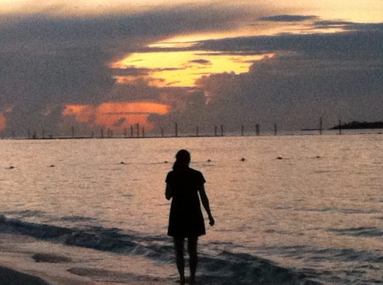 woman standing on the beach at sunset