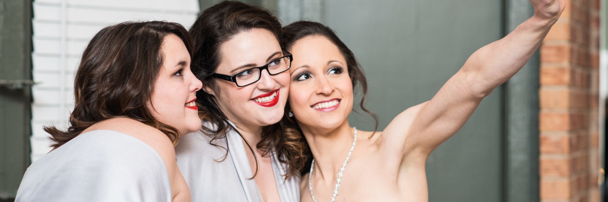 image of three women taking selfie and smiling, one wearing a wedding dress