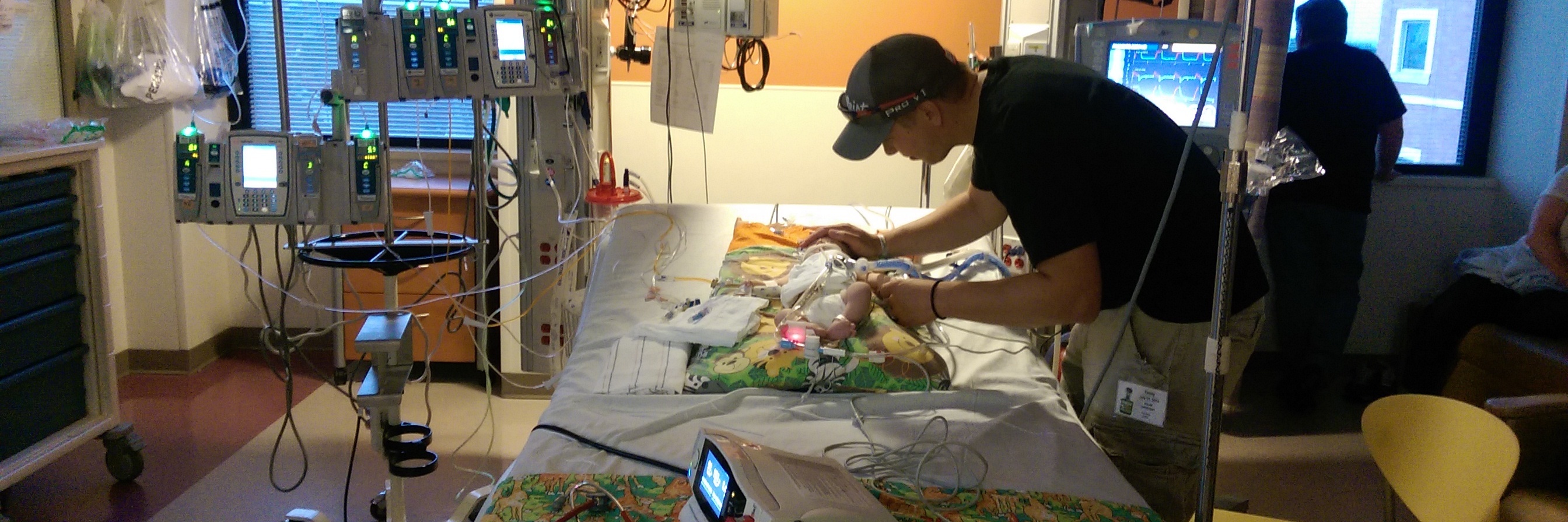 A Letter to My Son, From Your 'Heart Dad' The author standing next to his baby who is lying in a hospital bed