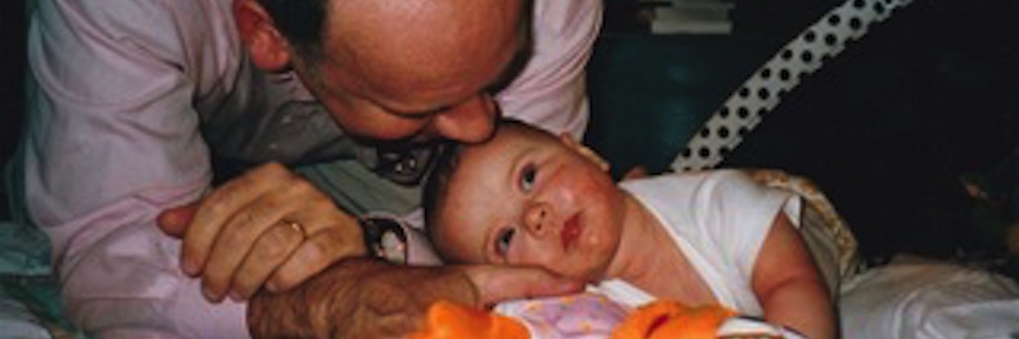 The 'Quiet' After Losing My Dad Father leaning over next to baby lying on blanket on floor with stuffed animal