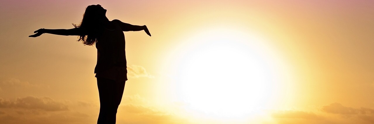 Not Owing People Explanations or Apologies for Chronic Illness woman standing on a pier over the ocean at sunset