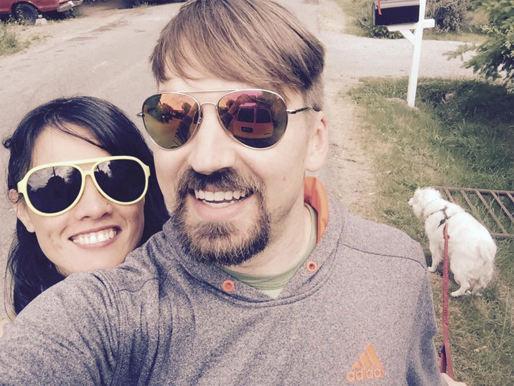 woman and man selfie smiling wearing sunglasses with dog in background