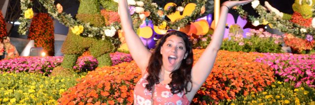 woman smiling and waving her arms in front of epcot at disney