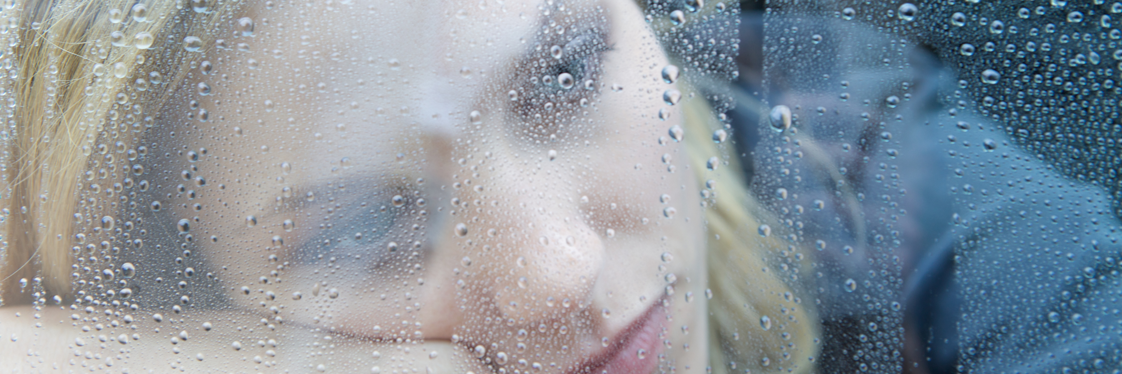 depressed woman resting head on arm near rainy window