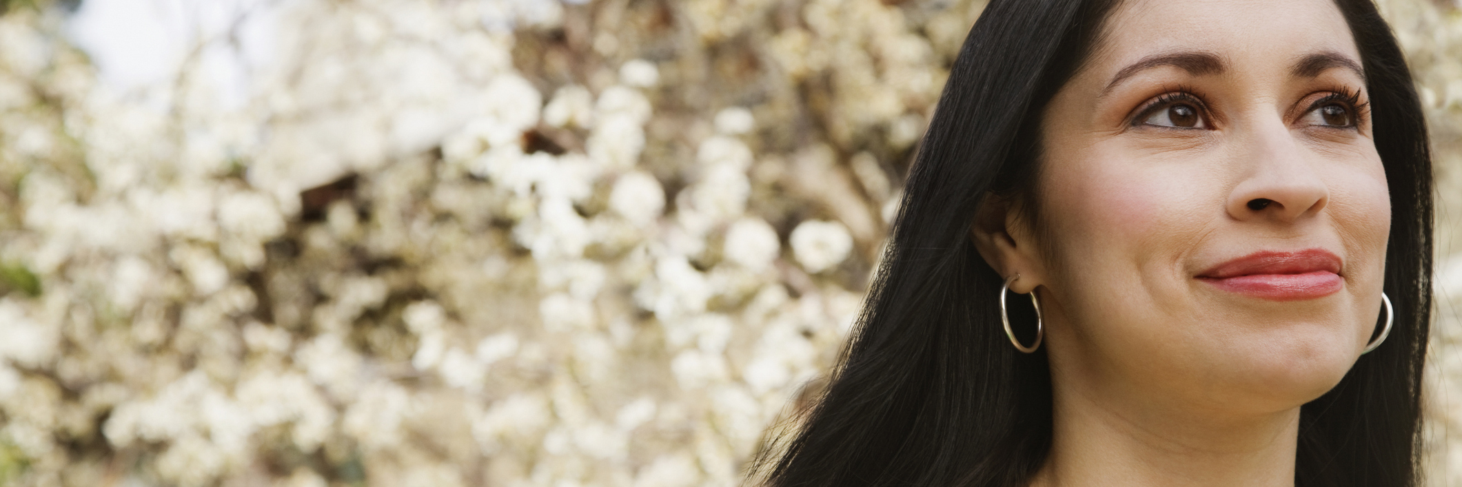 Managing Fibromyalgia, Chronic Illness and Practicing Self-Care woman smiling in front of a blossoming tree