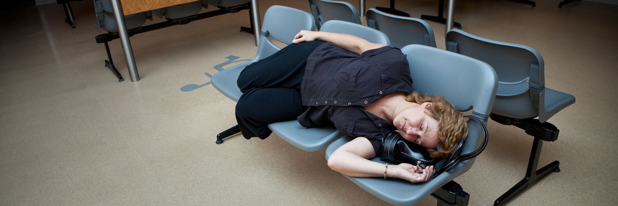 Woman laying on waiting room seats in the hospital.