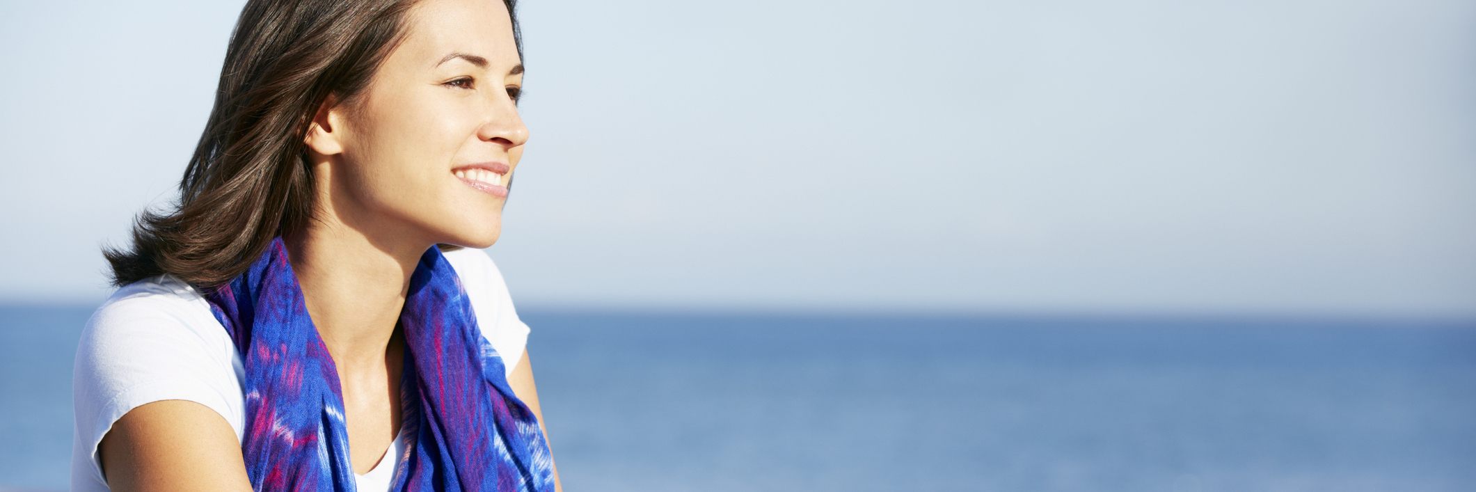 Why I'm Not Angry About Having a Chronic Illness woman smiling and leaning on a rail overlooking the ocean