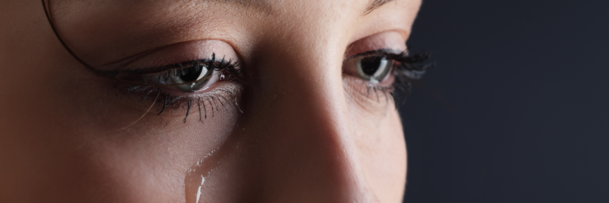 Trouble With Eye Contact in Therapy or Hard Conversations young woman with dark background with tear on cheek