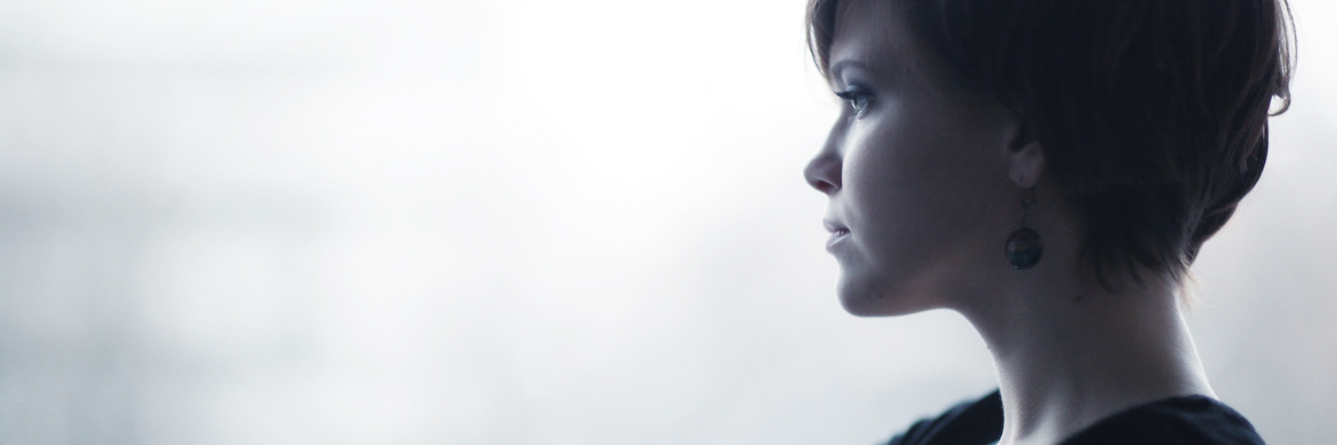 Woman sitting on windowsill indoors, looking out window