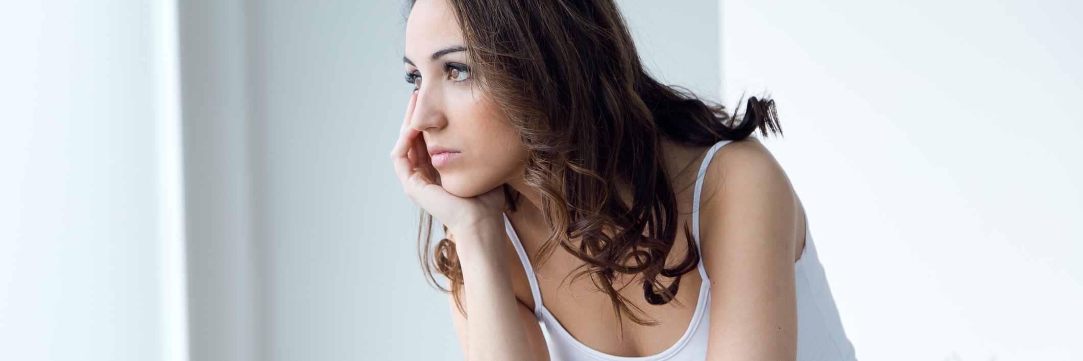 woman sitting on her bed and looking upset