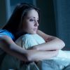 young woman sitting up in bed with insomnia