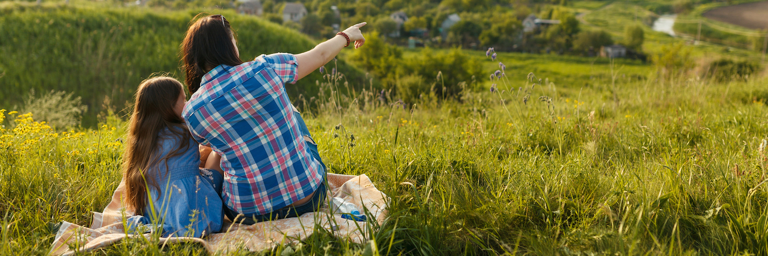 The Advice I Needed to Hear as a Parent of a Child With Disabilities Mom and daughter sitting on picnic blanket, with mom pointing out something in the tree-filled landscape