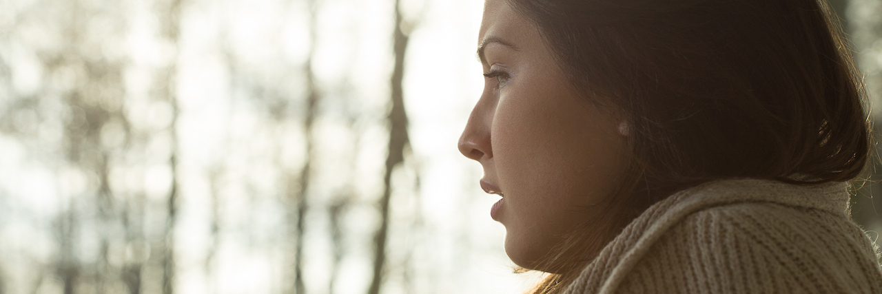 Living With Multiple Mental Illnesses Is Complicated A woman looking out the window at the woods