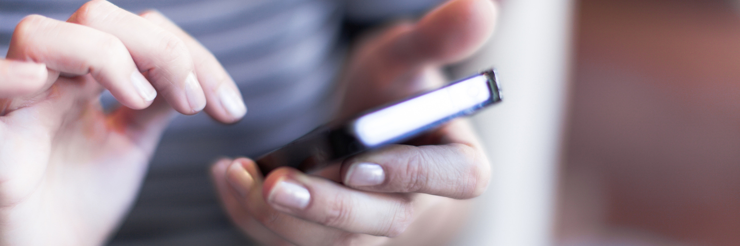 Things I Do When I Read a Story on The Mighty Person holding cell phone with one hand, with over hand about to touch the screen of the phone