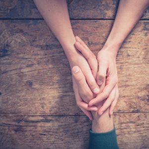 a person holding their friend's hand in support