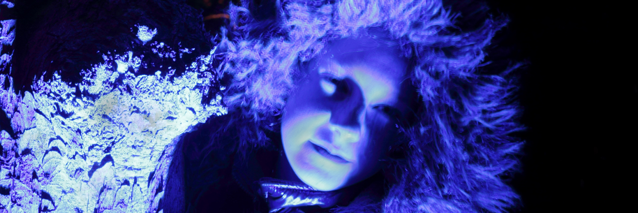 Living With Depersonalization Disorder Focus on blue illuminated treebark, a girl with furry hood next to it