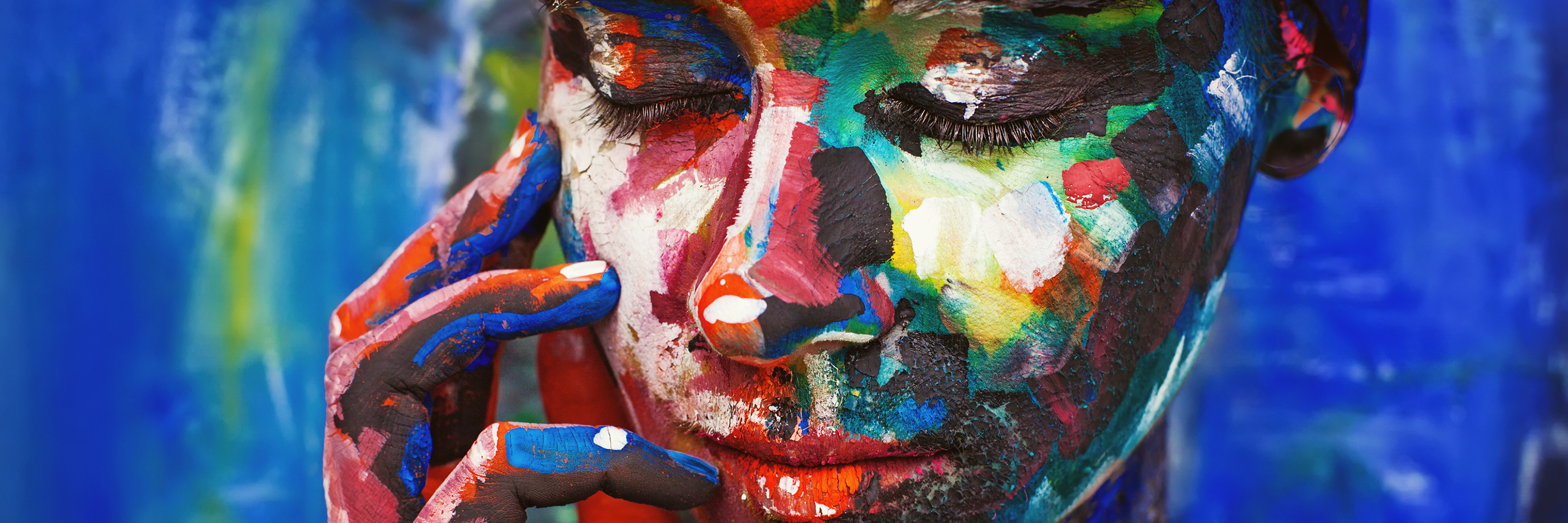 How Chronic Illness Changed my Priorities and Identity woman's face covered in colorful paint against a blue background