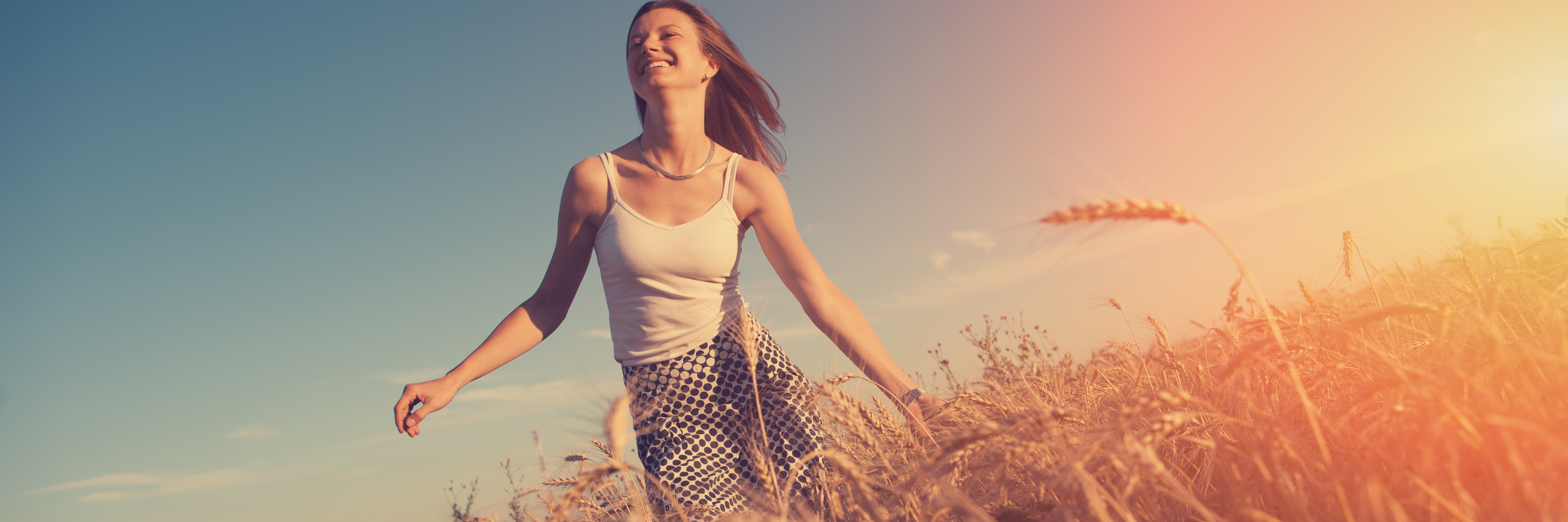 Why I Don't Hide My Self-Harm Scars in the Summer young woman running through field at sunset in summer wearing short sleeved top